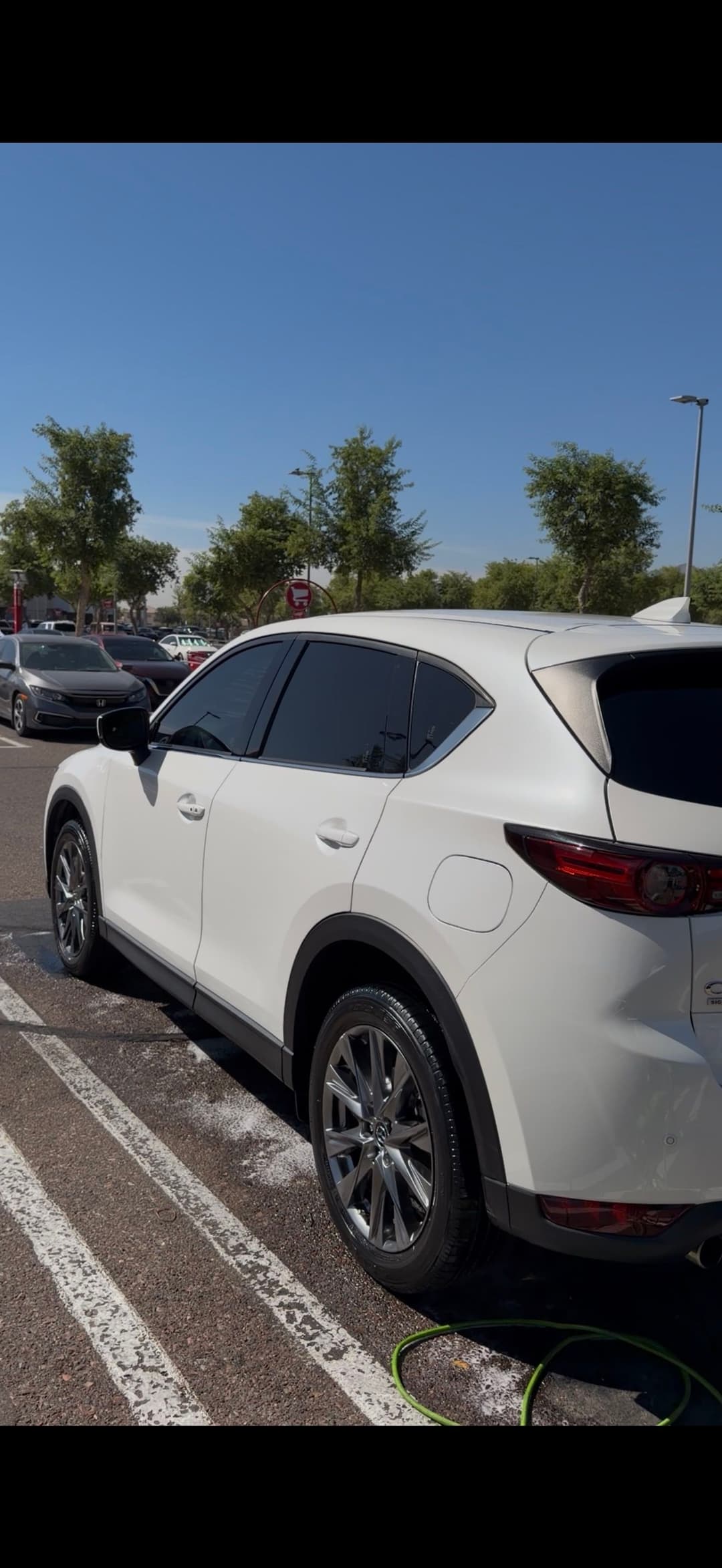 White SUV parked at a car wash under a clear blue sky. Clean and shiny exterior.