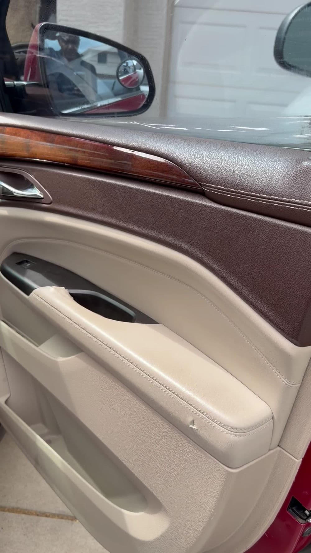Interior car door panel with leather and wood trim in a luxury vehicle.