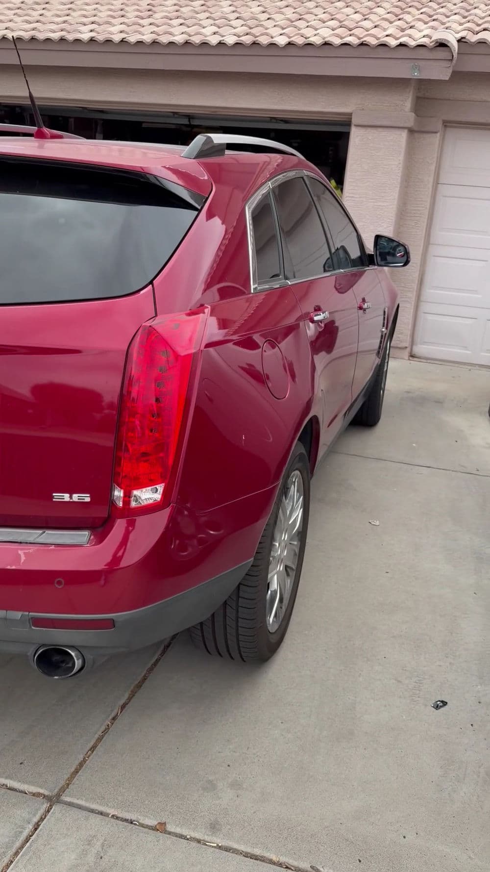 Red Cadillac SRX parked in driveway showcasing sleek design and shiny finish.