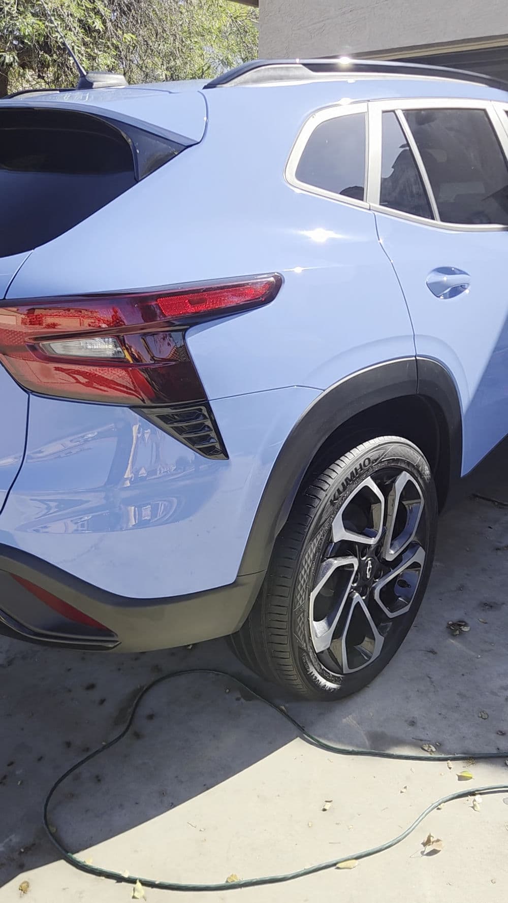 Light blue SUV parked, showcasing shiny rims and modern rear design details.