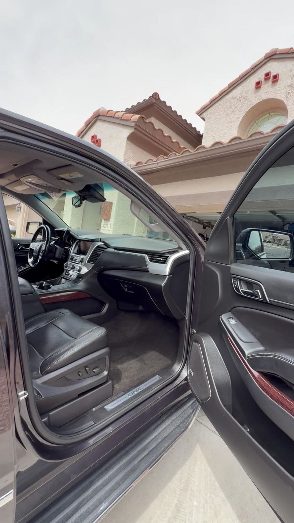 Luxury SUV interior with leather seating, dashboard details, and open doors.