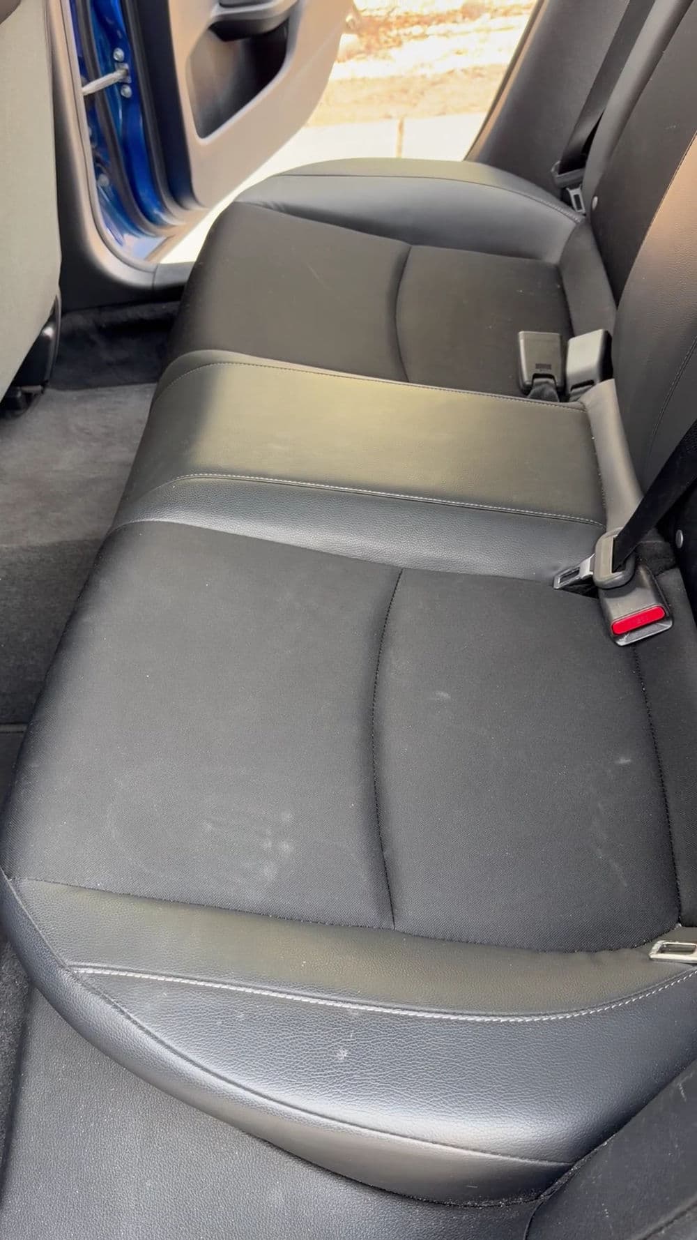 Black leather back seat of a car, showcasing comfortable design and clean upholstery.
