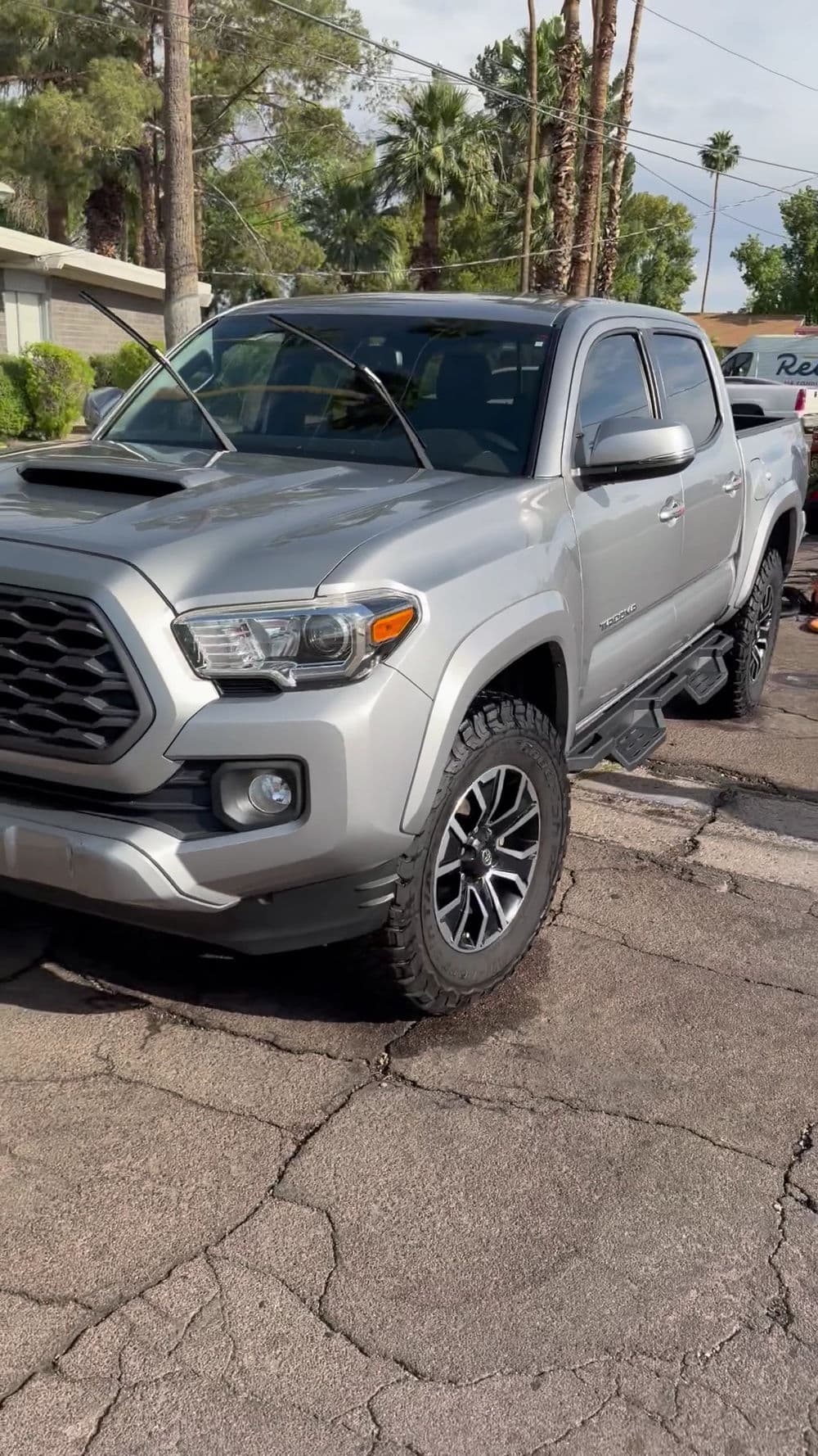 Silver Toyota Tacoma with black wheels parked on asphalt, featuring a sleek design and sporty grille.