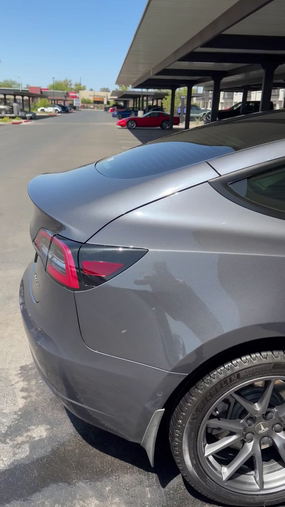Gray Tesla Model 3 parked outside, showcasing sleek design and modern features.