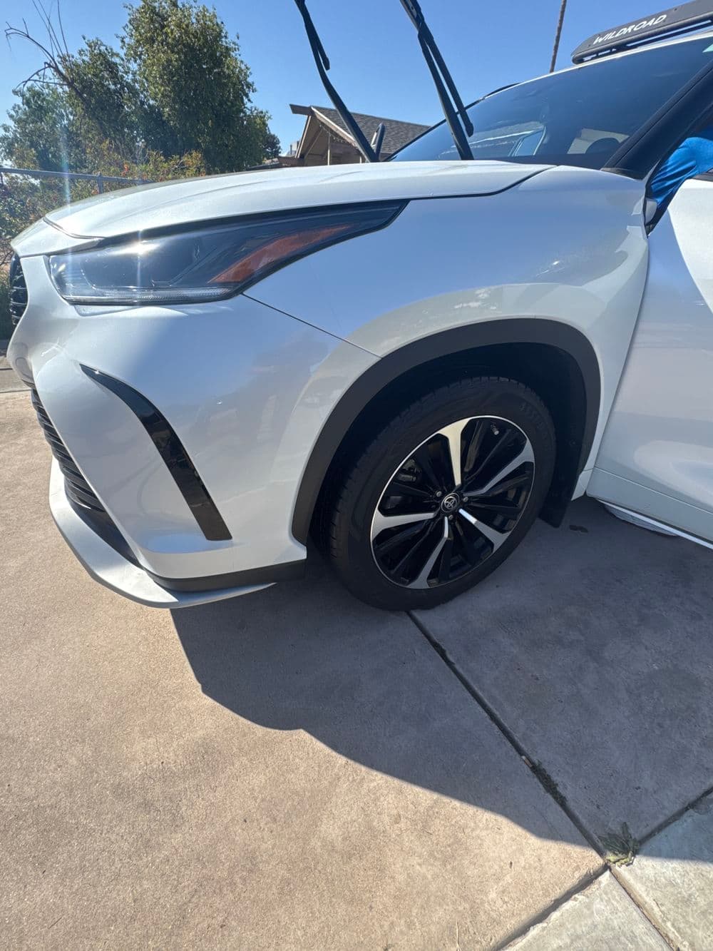 White luxury SUV with sleek design and black wheels parked in driveway under sunny sky.