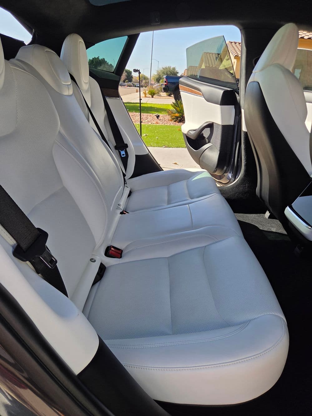 Interior view of a Tesla with sleek white leather back seats and modern design details.