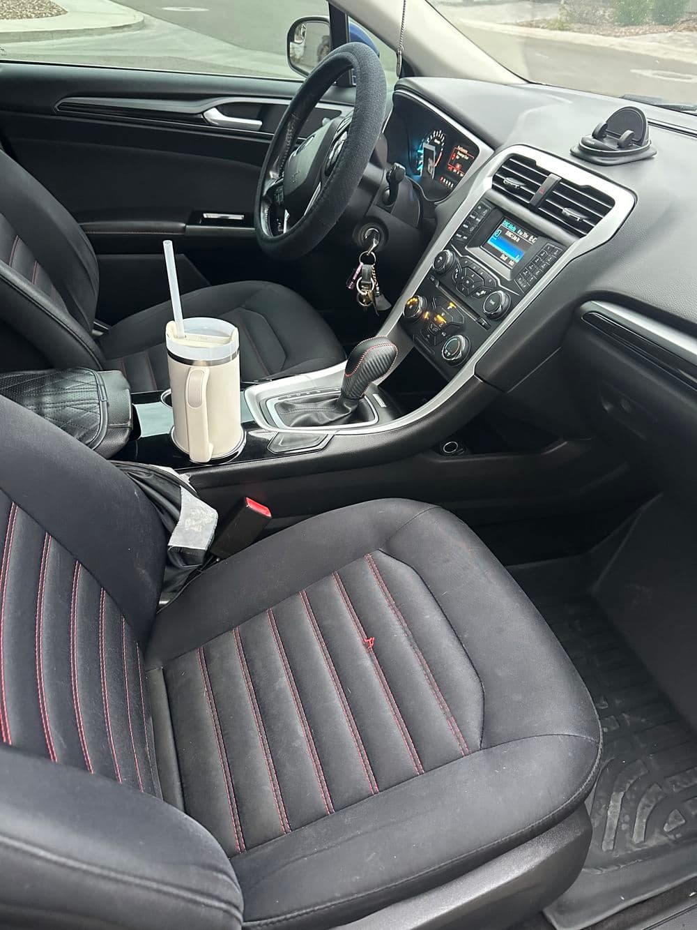 Interior view of a modern car showing front seats, dashboard, and console with cup holder.