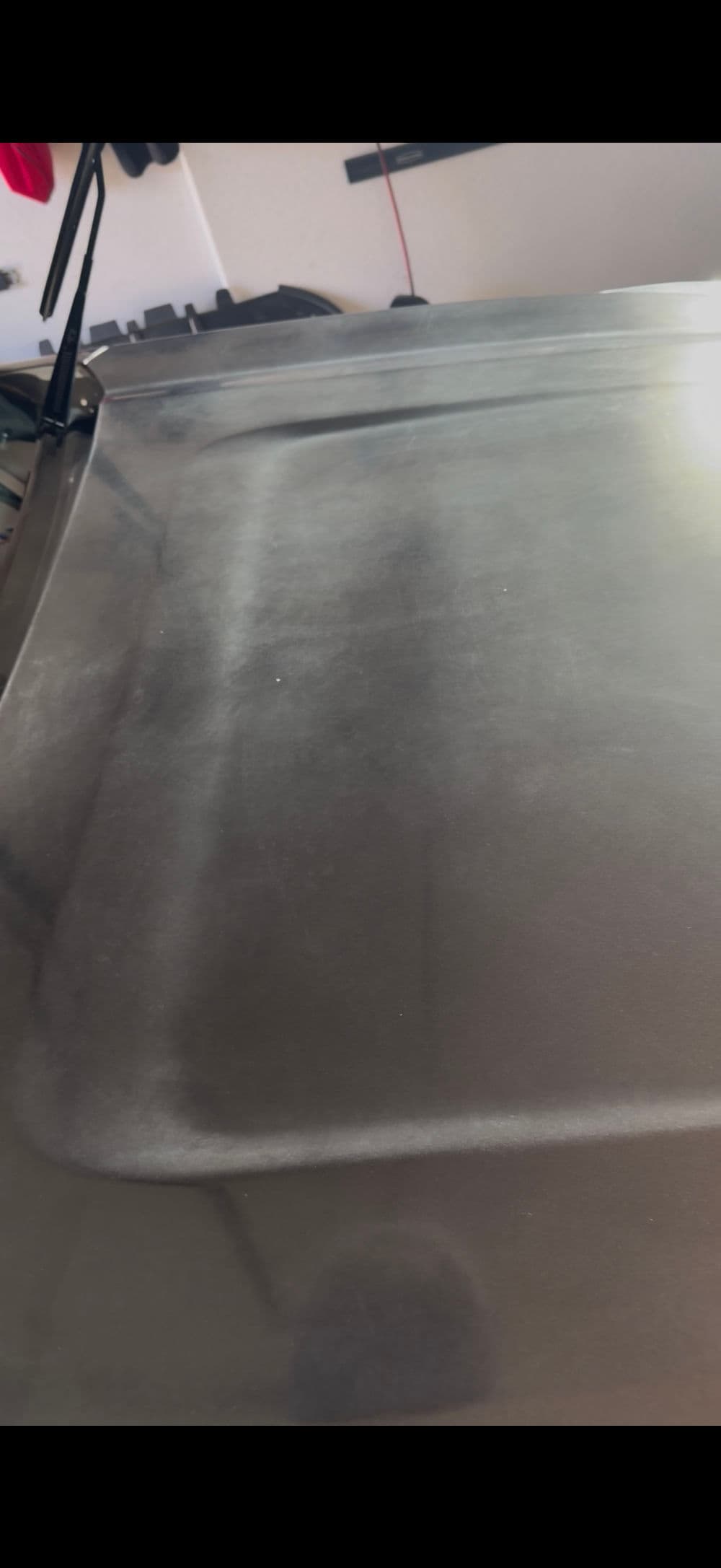 Close-up of a shiny, polished car hood reflecting soft light.