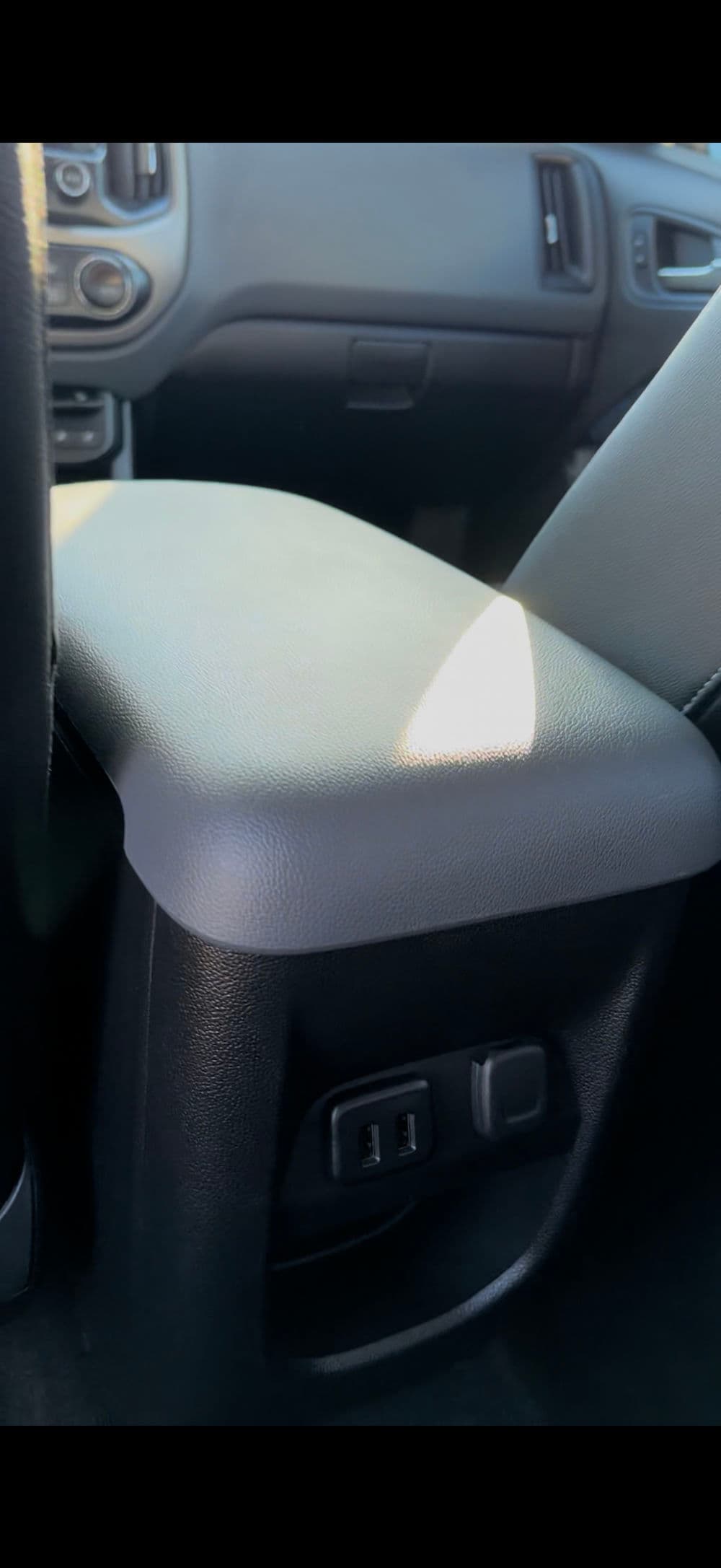 Armrest with storage and power outlet in a vehicle interior. Ergonomic and practical design.