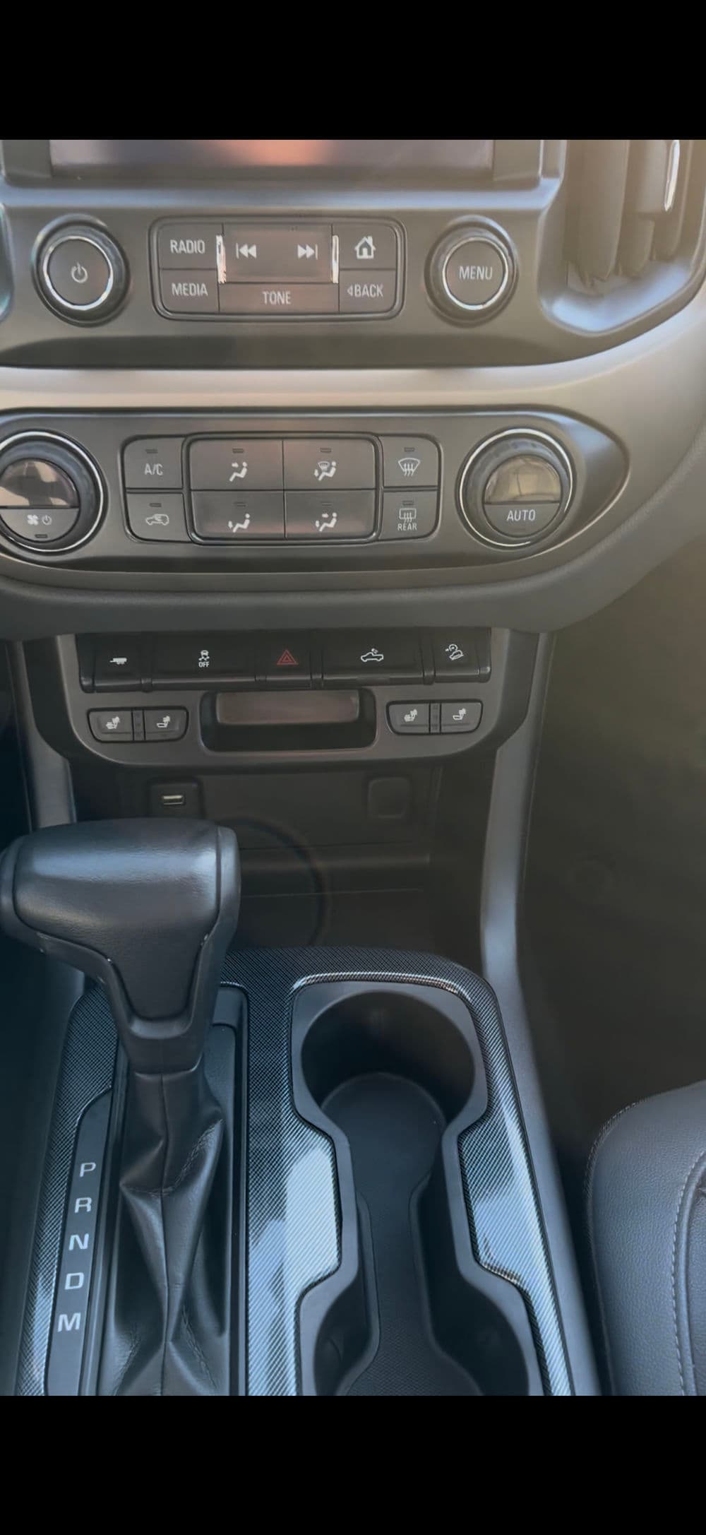 Car interior close-up featuring gear shift, climate control, and cup holder.