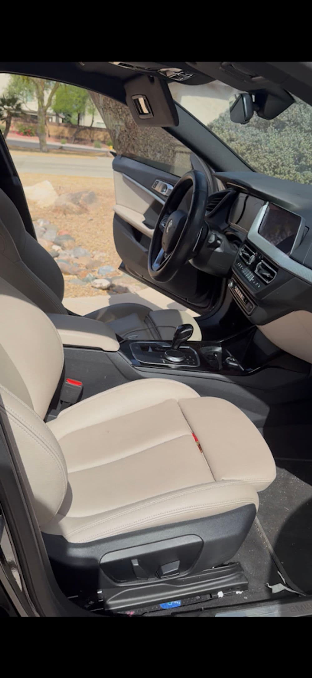 Interior view of a modern car with beige leather seats and a sleek dashboard.