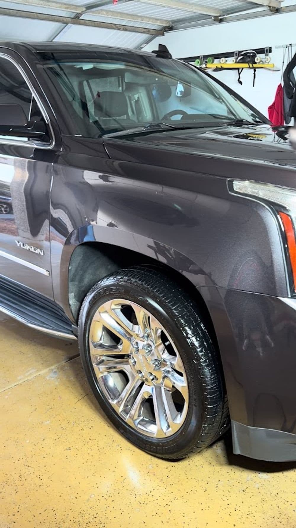 Close-up of a polished dark gray GMC Yukon showcasing shiny chrome wheels and detailed finish.