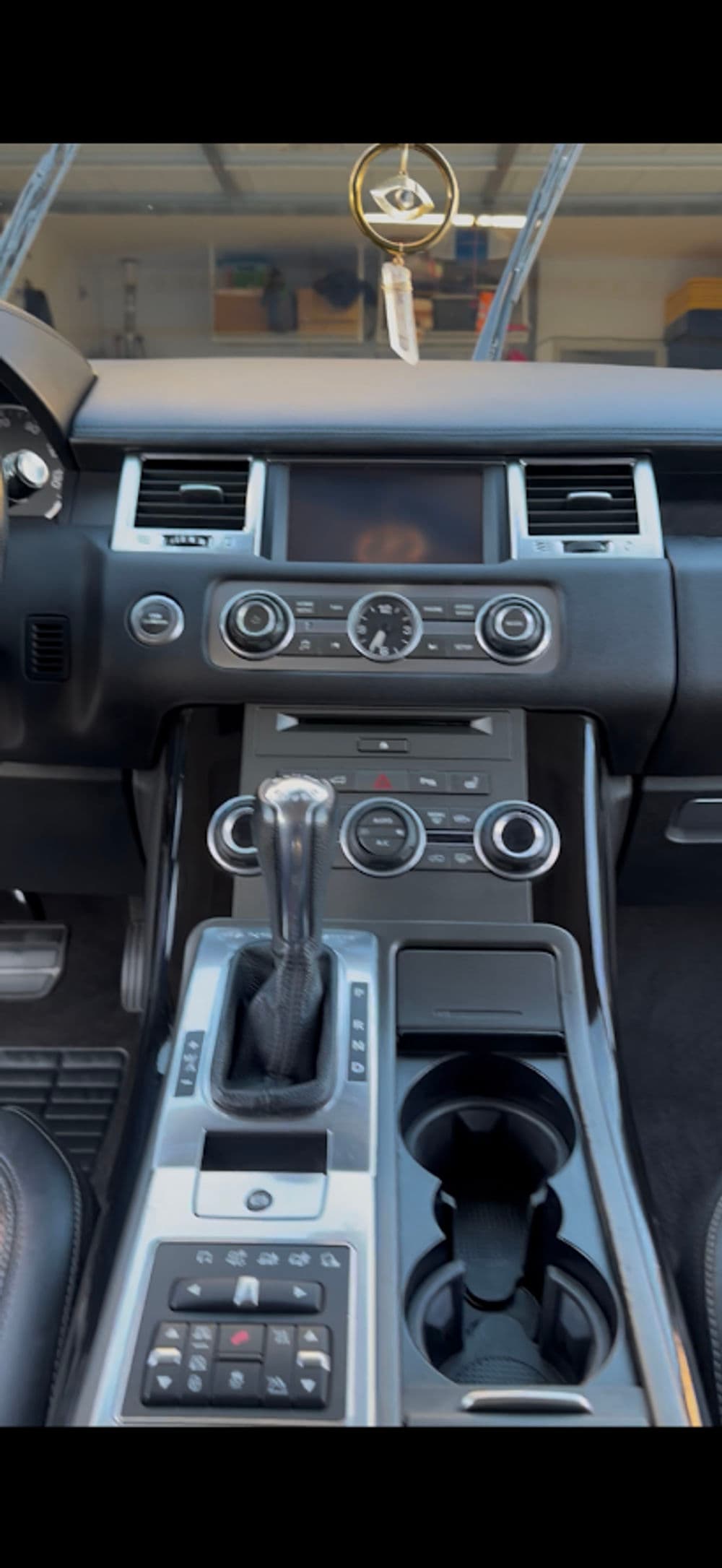 Interior view of a luxury car dashboard with control knobs and gear shift.