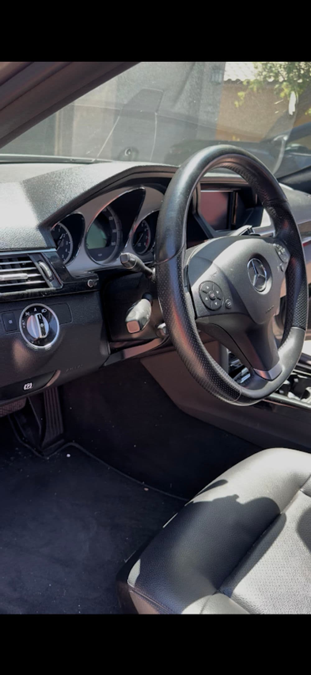 Mercedes Benz car interior featuring steering wheel, dashboard, and gear shift.