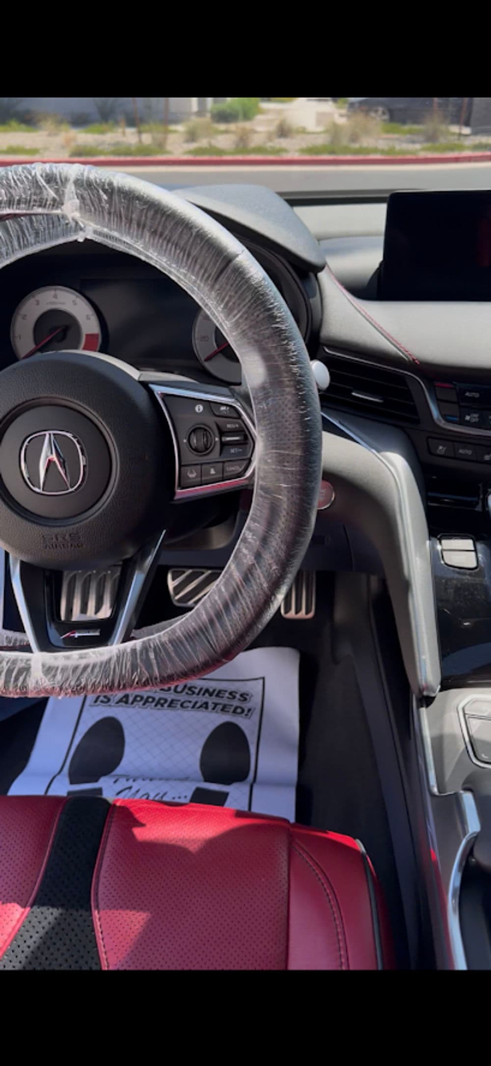 Interior of a car showcasing a steering wheel, dashboard, and red leather seats.