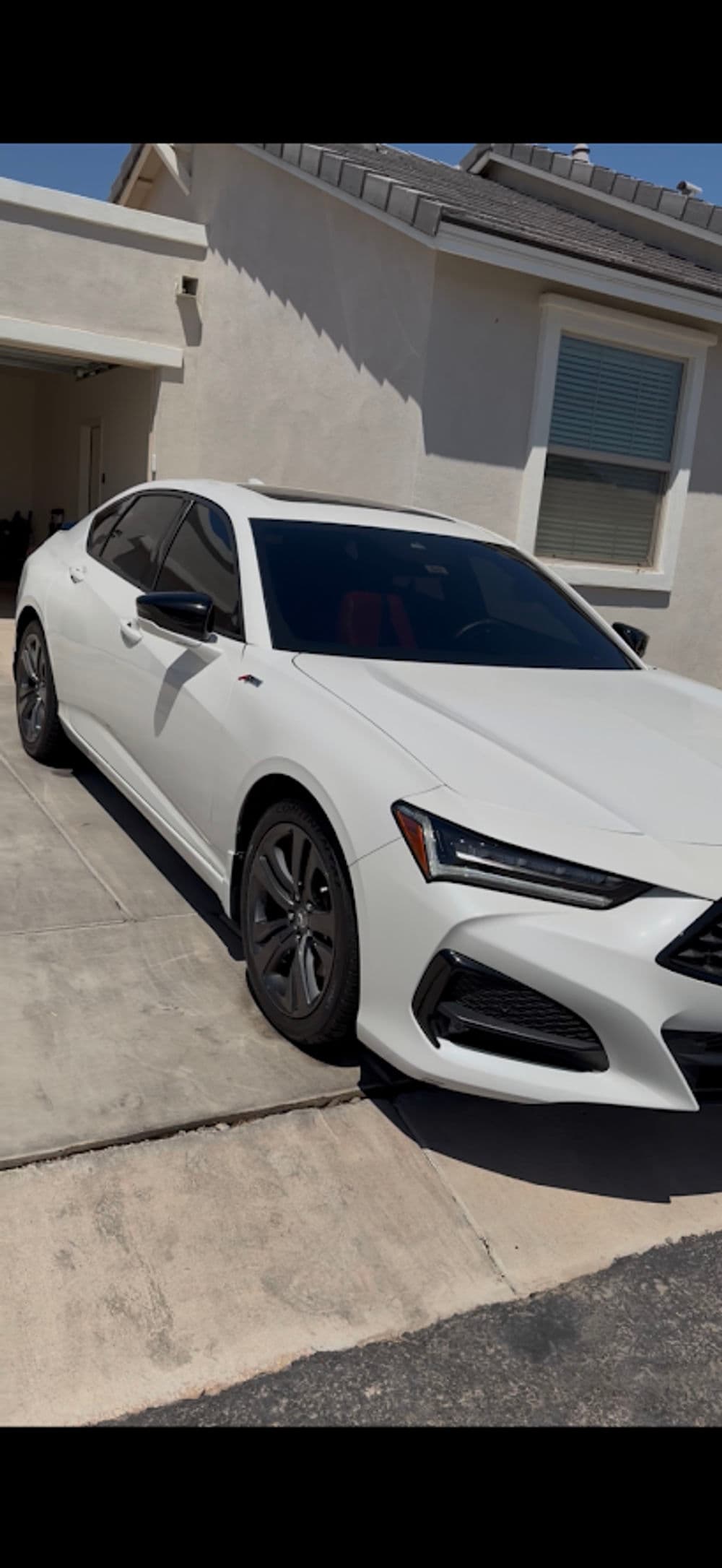 White luxury sedan parked in a driveway, featuring sleek design and tinted windows.