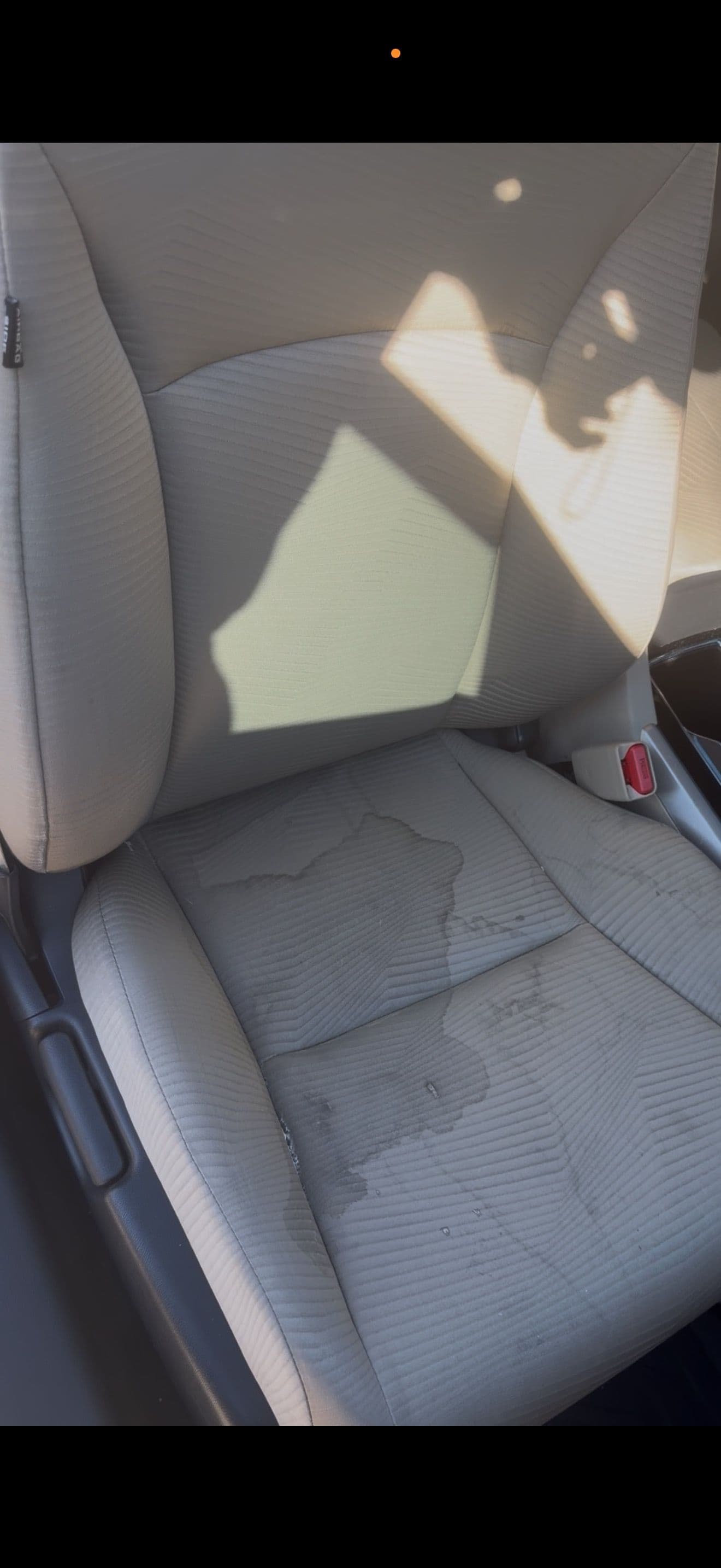 Wet car seat with a noticeable stain, highlighting potential water damage in a vehicle's interior.