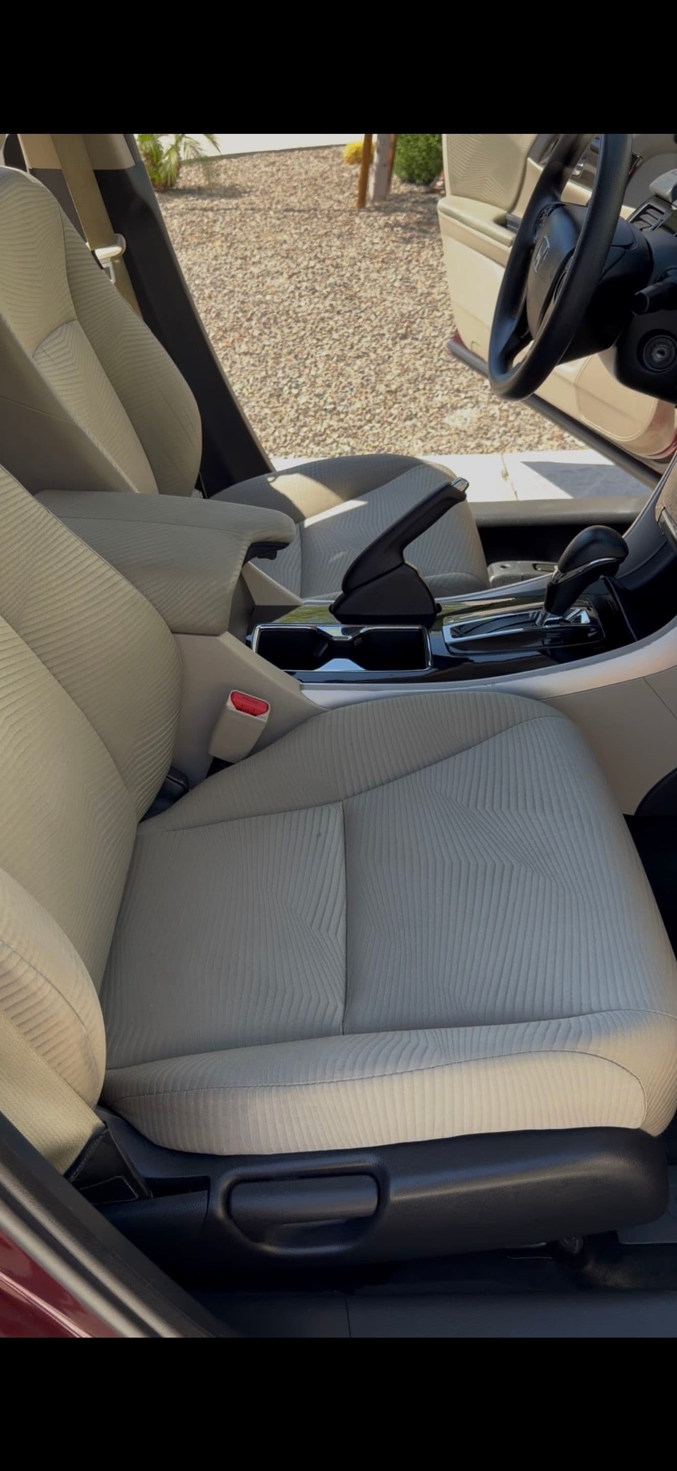 Interior view of a car showing beige fabric seats and center console.